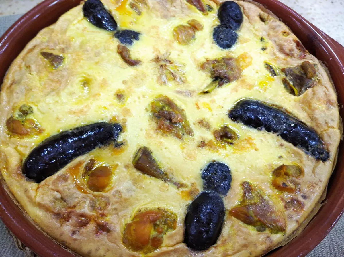 Detalle de la costra de huevo de un arroz con costra, con morcilla y garbanzos bajo la superficie dorada