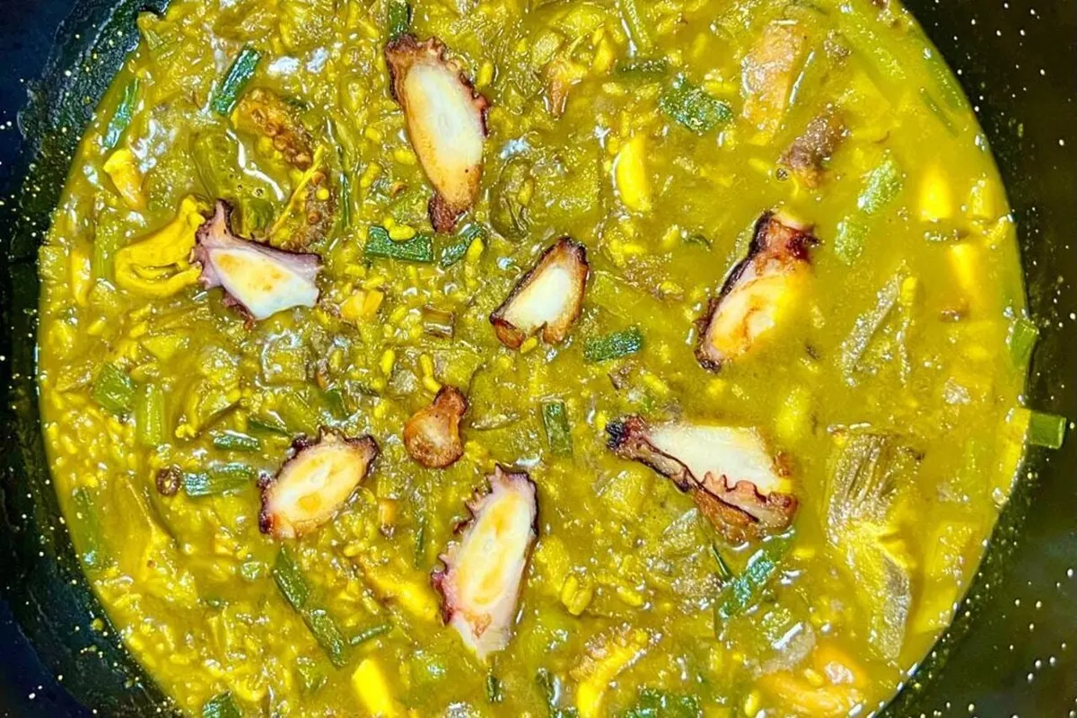 Arroz meloso de pulpo y alcachofas visto desde arriba, con trozos de pulpo a la plancha
