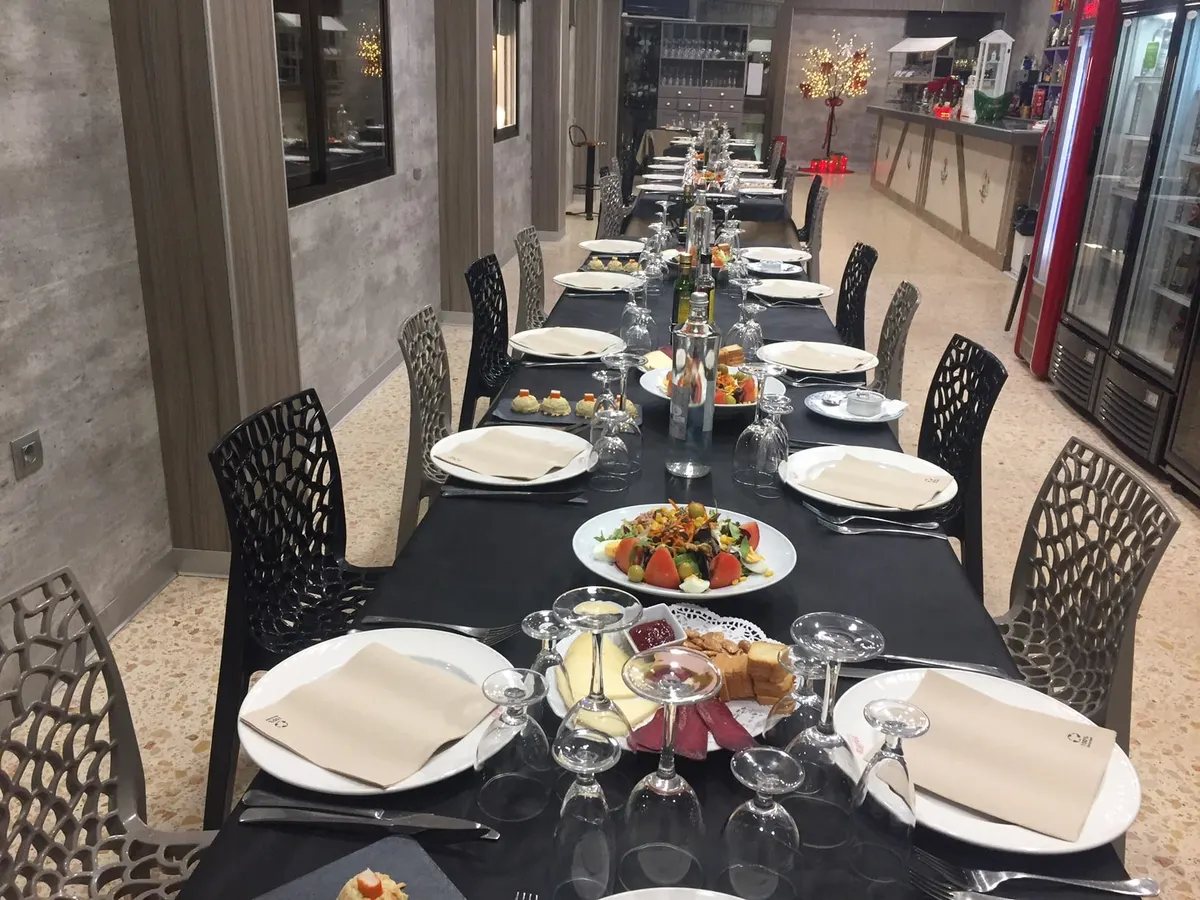 Mesa larga preparada para un grupo en nuestra sala, con mantel oscuro, ensaladas y copas